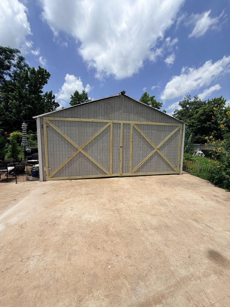 Metal garage building with new barn-style wood doors near Taylor, TX